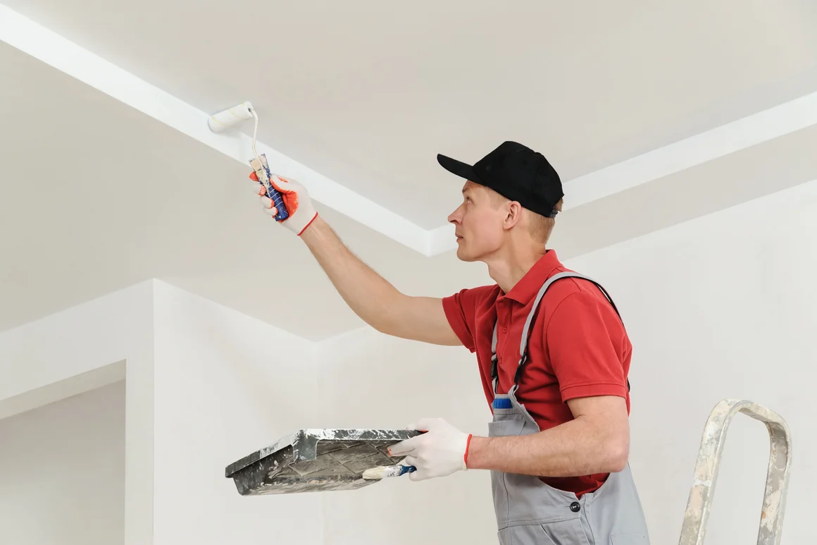 Person streicht Decke weiß